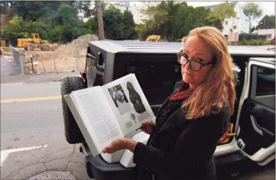  ?? ?? Kathleen Patricia Thrane holds a book depicting indigenous art, that she claims is similar to art on a cliff face at a pending developmen­t site along West Main Street in Stamford last week.