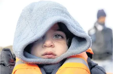  ?? REUTERS ?? A Syrian refugee child wearing a lifejacket looks on moments after arriving on a raft with other Syrian refugees on a beach on the Greek island of Lesbos on January 4.