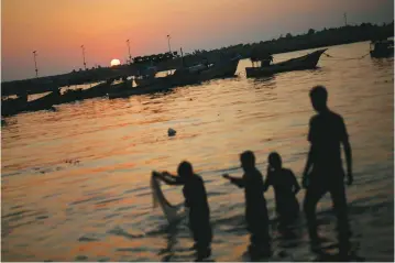  ??  ?? PALESTINIA­N YOUTH use a net as they fish during sunset at the seaport of Gaza City.