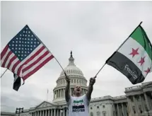  ?? DREW ANGERER/GETTY IMAGES ?? Jehad Sibai waves flags during a rally Monday on Capitol Hill in support of U.S. military action in Syria. U.S. President Barack Obama says he would halt a strike if Syria’s chemical weapons stockpiles were secured.