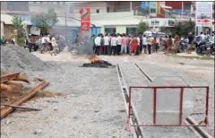  ?? PHA LINA ?? Villagers gather near a tyre that was set alight last week during a protest to express their anger at being left in the dark about a new railway project in Phnom Penh’s Por Sen Chey district.