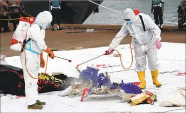  ?? Tatan Syuflana Associated Press ?? WORKERS spray disinfecta­nt on parts of Sriwijaya Air Flight 182, which crashed Saturday into the Java Sea, at Tanjung Priok port on Sunday in Jakarta, Indonesia. The airliner was carrying 62 Indonesian nationals.