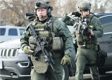  ?? ANTONIO PEREZ / CHICAGO TRIBUNE VIA THE ASSOCIATED PRESS ?? Police officers armed with rifles gather at the scene where an active shooter was reported in Aurora on Friday.