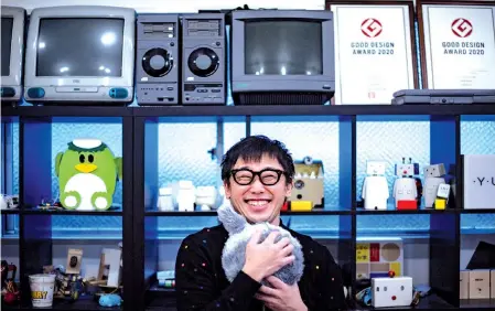  ??  ?? Aoki hugging robotic cushion Qoobo in a studio in Tokyo.