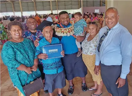  ?? Photo: Salote Qalubau ?? Clement Victor (garlanded), with his family after the graduation ceremony at Fulton Adventist University College in Sabeto, Nadi, on November 27, 2022.