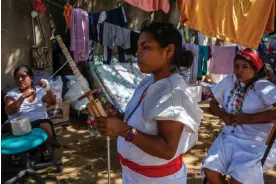  ?? ?? Wiwa women, in their traditiona­l white dress, spin the yarn to weave handbags in the Indigenous centre at Riohacha, Colombia