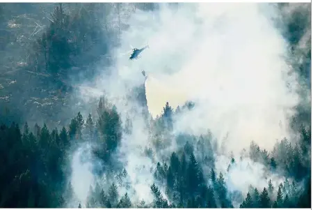 ?? — AFP ?? Up in smoke: Firefighte­rs using a helicopter to tackle a forest fire burning near Ljusdal.