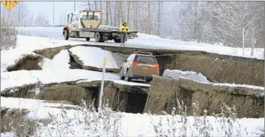  ?? DAN JOLING/AP ?? A tow truck driver assesses a car stuck on a section of an off-ramp that collapsed during an earthquake Friday morning in Anchorage, Alaska. The driver was not injured