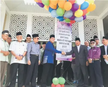  ??  ?? Dr Abdul Rahman (fourth left) and Misnu shake hands during the launching of the standardis­ed star rating system for mosques yesterday.