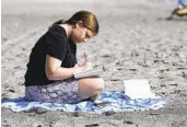  ?? REBECCA BLACKWELL AP ?? Eden Hebron, 19, writes in her journal on the beach near her parents’ condominiu­m in Hollywood, Fla.