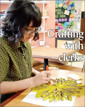  ??  ?? Ashdon Wilson, clerk at the Pea Ridge Community Library, constructs a craft while video-taping herself using her cellphone.
(NWA Democrat-Gazette/Annette Beard)