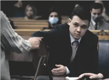  ?? SEAN KRAJACIC/THE KENOSHA NEWS VIA AP ?? Kyle Rittenhous­e pulls numbers of jurors out of a tumbler during his trial at the Kenosha County Courthouse in Kenosha, Wis., on Tuesday.