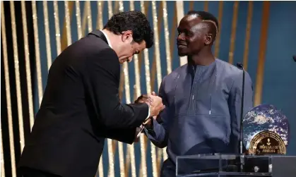  ?? Photograph: Benoît Tessier/Reuters ?? Sadio Mané receives the Socrates award from the late Brazilian’s brother, Rai.