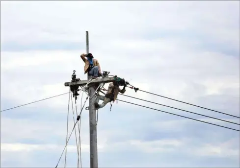  ?? HONG MENEA ?? Two men work on connecting electricit­y cables in Kampong Speu province last year.