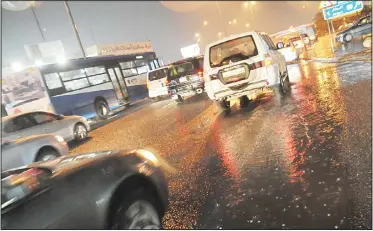  ?? Photo by Saud Salem ?? Vehicles making their way through pools of water that resulted from showers of rain that fell in Kuwait Sunday evening.
