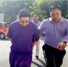  ??  ?? Wong being led to court for his hearing yesterday. — Bernama photo