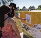  ?? Allen J. Schaben Los Angeles Times ?? CAITLIN HARJES, left, and Angel Santiago place their ballots into an off icial drop box in Santa Ana.