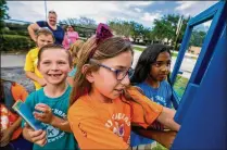  ?? RICHARD GRAULICH / THE PALM BEACH POST ?? Jerry Thomas Elementary students Joey Scolly (left), 6; his sister Taylor, 9; and Gabby Puddu, 9, grab books June 1 from the new Little Free Library at the corner of Toney Penna and Maplewood drives in Jupiter. The library just outside the school will be available to students and the public year-round.