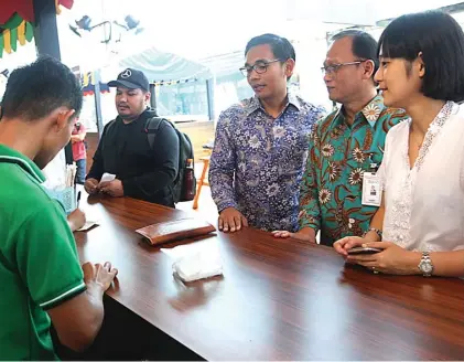  ?? IMAM HUSEIN/JAWA POS ?? TEROBOSAN: SEVP Teknologi Informasi BNI Dadang Setiabudi (dua dari kanan) bersama CEO Go-Pay Aldi Haryoprato­mo (tiga dari kanan) dan CEO Go-Food Catherine Hindra Sutjahyo (kanan) di salah satu booth Go-Food Festival di Jakarta kemarin.