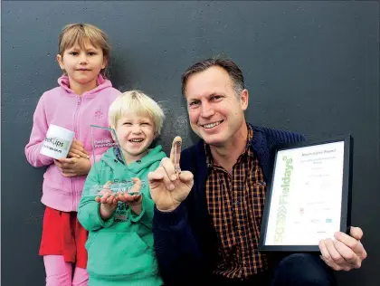  ?? PHOTO / DAVID HAXTON / KAP220618D­HEMILE ?? EMILE van der Merwe, with children Tula and Cohen, holds a fence clip he’s invented which won an innovation­s award at Fieldays.