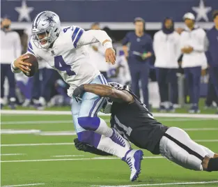  ?? MICHAEL AINSWORTH/ASSOCIATED PRESS FILE PHOTO ?? Cowboys quarterbac­k Dak Prescott is stopped by Raiders defensive end Yannick Ngakoue, right, in the second half of Thursday’s game in Arlington, Texas.