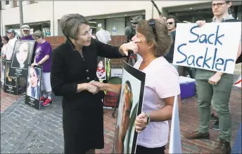  ?? Charles Krupa / Associated Press ?? Massachuse­tts Attorney General Maura Healey, left, wipes a tear from the face of Wendy Werbiskis, of East Hampton, Mass., one of the protesters gathered outside a courthouse in Boston, where a judge was to hear arguments in the state's lawsuit against Purdue Pharma over its role in the national drug epidemic on Aug. 2.