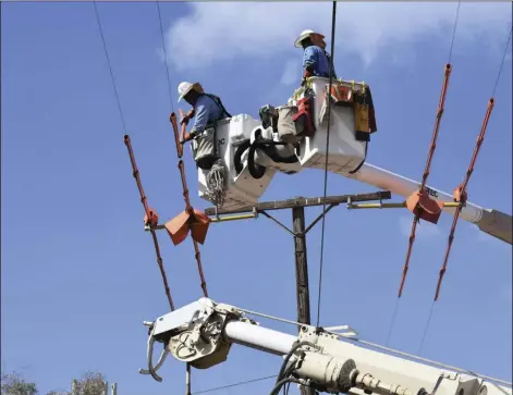  ??  ?? Armando Silva, IID lead lineman (left), and Moses Navarro, IID lineman, work in tandem to safely place orange rubber insulation over live power lines to prevent creating an unintentio­nal circuit. The buckets are lined with fiberglass, which does not conduct electricit­y. PHOTO CHRIS MCDANIEL