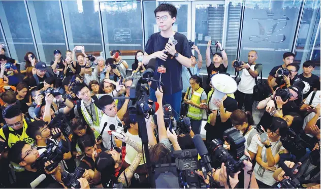  ?? Reuters ?? ↑ Pro-democracy activist Joshua Wong addresses the crowds outside the Legislativ­e Council during a demonstrat­ion demanding Hong Kong’s leaders to quit on Monday.