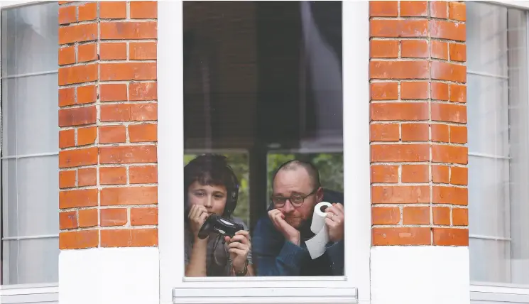  ?? Yves Herman / reuters ?? Resident Laurent Lanthier and his son Robin, 12, behind the window of their home during a coronaviru­s lockdown imposed by the Belgian government.