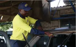  ?? ?? A Windscreen Fitment Centre worker, Parcival Siriva, replacing a client’s a car windscreen in the workshop