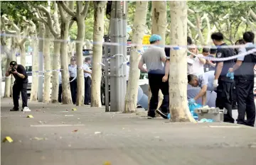  ??  ?? Police officers work at the scene after a man armed with a knife attacked students at the entrance to a primary school, in Xuhui district of Shanghai. — Reuters photo