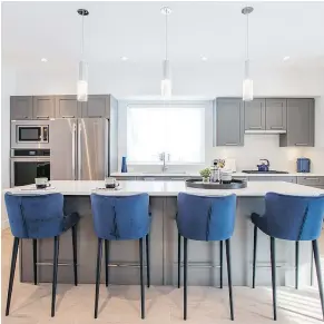  ??  ?? The blue velvet counter stools work well set against the stone counter and grey cabinets of this showhome kitchen at Fairways.