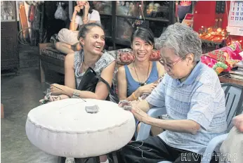  ??  ?? Tourists observe how locals make cushions used in Chinese shrines.