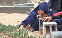  ?? ?? A woman cries over a grave Wednesday at the start of the Eid al-Fitr festival, marking the end of the Muslim holy month of Ramadan, at a cemetery in Rafah in the southern Gaza Strip.