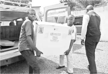  ?? — Reuters photo ?? Congolese Health Ministry officials carry the first batch of experiment­al Ebola vaccines in Kinshasa, Democratic Republic of Congo.