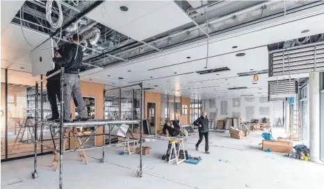  ?? FOTO: CHRISTIAN FLEMMING ?? Es geht voran auf der Inselhalle­nbaustelle: So bauen Arbeiter hier in einem der Konferenzr­äume die Deckenverk­leidung ein.