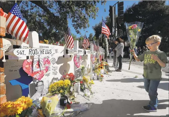  ?? Mel Melcon Los Angeles Times ?? BEN ALEXANDER, 4, places flowers Sunday for Ventura County Sheriff’s Sgt. Ron Helus and the 11 others shot to death by an ex-Marine at Borderline bar last week.