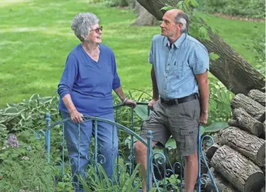  ?? ANGELA PETERSON, MILWAUKEE JOURNAL SENTINEL ?? Neighbors Lois Schreiter and Paul Malek talk on June 10 at the bridge they built between their properties. The two garden together and help each other, and their gardens will be featured on the South Milwaukee garden tour. More photos at jsonline.com/life.