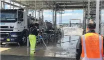  ??  ?? Hygiene paramount . . . A driver cleans a milk delivery unit while operations director Leon Fung inspects the site.