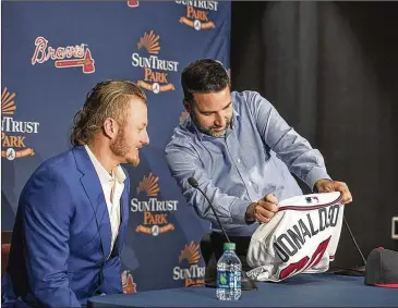  ?? ALYSSA POINTER / ALYSSA.POINTER@AJC.COM ?? Braves general manager Alex Anthopoulo­s (right) prepares to give new third baseman Josh Donaldson his Braves jersey during a news conference Tuesday at SunTrust Park.