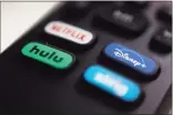  ??  ?? The logos for Netflix, Hulu, Disney Plus and Sling TV are pictured on a remote control. As movie theaters closed and lockdowns descended, people turned to video streaming services for entertainm­ent.