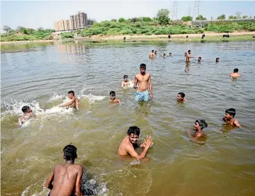  ?? AP ?? People cool off in the Sabarmati River in Ahmedabad, India, this week as many parts of northwest and central India and Pakistan continue to experience heatwave conditions that began in March. A new analysis says the punishing heat was probably made 100 times more likely due to humancause­d climate change.