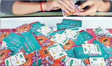  ?? LINA PHA ?? An employee sorts mobile phone SIM cards last year at a shop in central Phnom Penh. The Ministry of Post and Telecommun­ications has gone 50-50 in a deal with telecoms to being mobile service to rural areas.