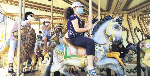  ??  ?? People wearing protective masks ride a carousel at an amusement park in Istanbul, Turkey, July 10, 2021.