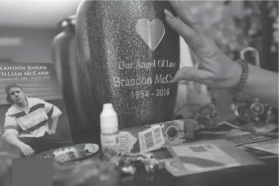  ?? PHOTOS: JASON KRYK ?? Lisa McCann touches the urn holding her son Brandon McCann’s ashes. It sits on a dresser in his bedroom at her home.