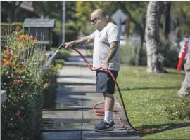  ?? Francine Orr Los Angeles Times ?? SCOTT MOSES waters f lowers in his frontyard in South Pasadena. Many water suppliers are offering rebates for replacing lawns with drought-tolerant gardens.