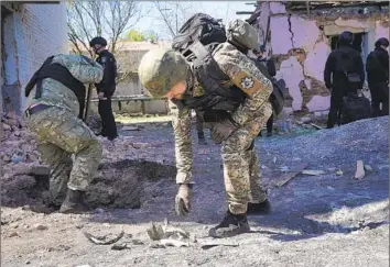  ?? Andrii Marienko Associated Press ?? A POLICE officer examines fragments of a bomb after a Russian air raid in Kharkiv, Ukraine, last month. On Friday, Russia pounded a town elsewhere in the northeast with artillery, missiles and guided aerial bombs.