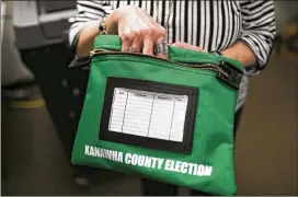  ??  ?? Vera McCormick, the Kanawha County Clerk, demonstrat­es new protocols for handling voting materials March 20 in Charleston, W.Va. The state has embraced cybersecur­ity with an enthusiasm greater than many other states.