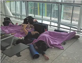  ?? AP PHOTO ?? People rest on the floor in Terminal 5 at Heathrow airport on Friday.