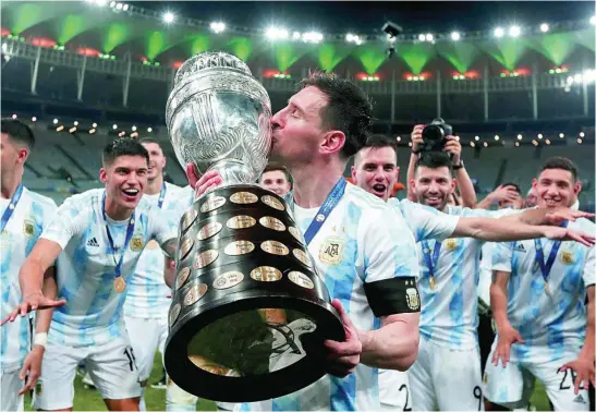  ?? AP ?? Leo Messi besa la Copa América mientras sus compañeros de selección esperan detrás